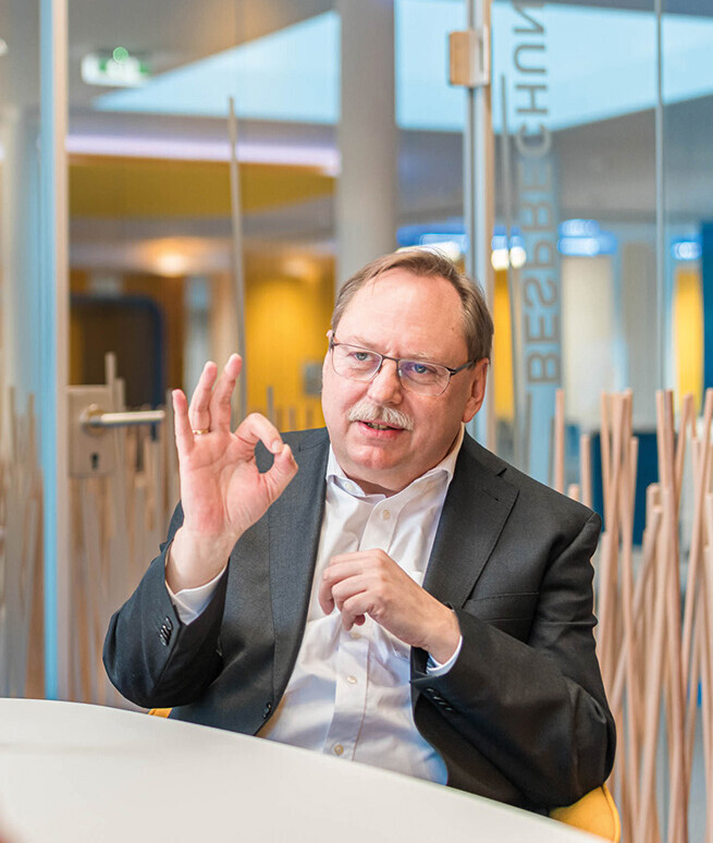 Foto von Prof. Dr. Gerloff in weißem Hemd und grauem Sakko in einer Gesprächssituation. Er formt die rechte Hand zum OK-Zeichen.
