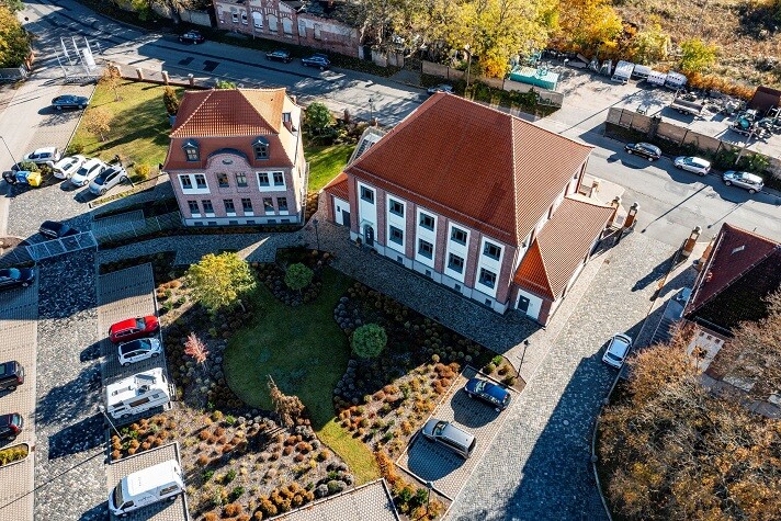 Luftbildaufnahme vom Gaswerk mit Grünanlage und Parkplatz im Sonnenschein.