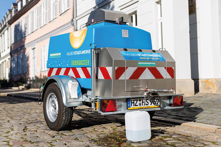 Der Trinkwasserwagen der Halberstadtwerke steht vor einem Haus und füllt einen Kanister mit Wasser.