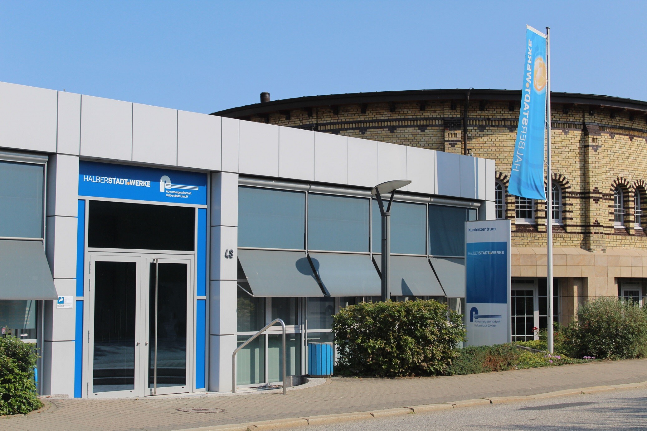 Das Kundenzentrum bei blauem Himmel von außen fotografiert, aus Richtung Wehrstedter Straße mit Rotunde.